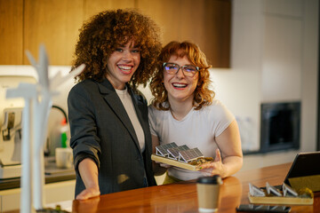Businesswomen with solar panels model smiling at camera at office.