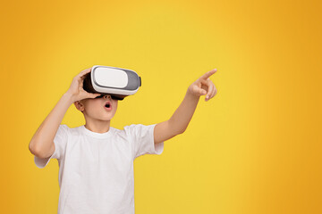 Wow, its amazing. Boy experiencing virtual reality, gesturing on orange studio background, copy...