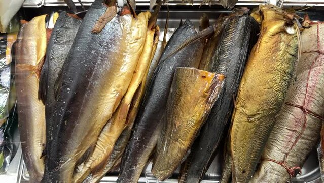 Fragment of cold smoked mackerel and Atlantic salmon on a substrate for sale in the supermarket. Close-up