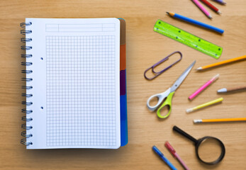 Open notepad on blurred background with different stationery. Planning, checklist, schedule. Template for office, school, shopping list, preparation for school.