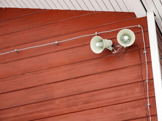 A dual loudspeaker system is mounted on a rustic red wooden wall, wired meticulously across the...