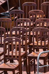 Brown wooden chairs are arranged in rows next to each other. Selective focus.