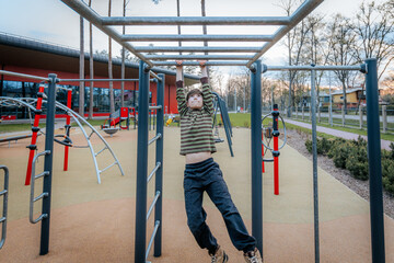 Fototapeta premium boy was hanging upside down on the bars. Smiling happy child