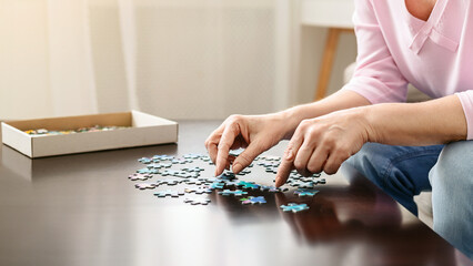 Alzheimer's disease and dementia prevention. Senior woman playing jigsaw puzzle on wooden table at...