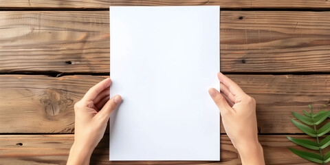 Hands Holding Blank White Paper on a Wooden Table