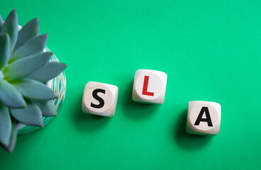 SLA - Service Level Agreement. Wooden cubes with word SLA. Beautiful green background with...