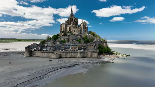Aerial view of the famous French landmark Abbaye du Mont-Saint-Michel at brighter day with beautiful white clouds. Normandie. France.