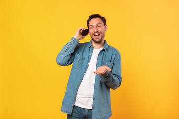 A man is holding a cell phone up to his ear, engaging in a phone conversation. He appears focused...