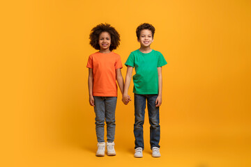 Two African American kids are standing shoulder to shoulder, looking straight ahead. They are both...