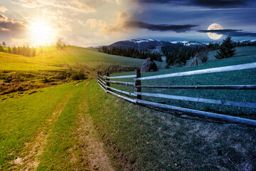 rural landscape in mountains on spring equinox. wooden fence along the path through grassy fields...
