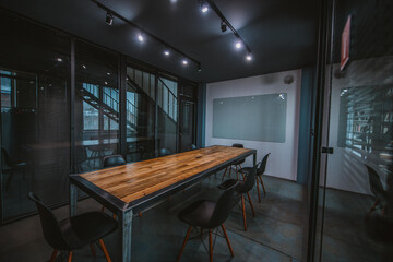 Modern spacious stylish office in loft style. Meeting room with a large wooden table behind glass...