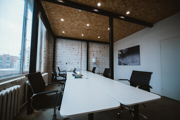 Modern spacious stylish office in loft style. Meeting room with a large wooden table near a large...