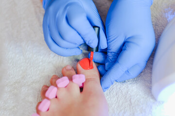 The master gives a pedicure to the client. Gel polish coating. Close-up.