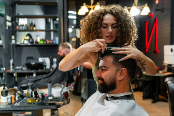 Male client smiling as a skilled barber cuts his hair, reflecting a friendly and enjoyable atmosphere in the barber shop.