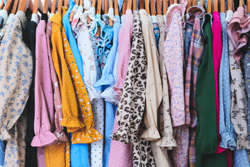 A rack of clothes with a variety of colors and patterns. The clothes are hanging on a clothesline,...