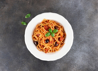 Spaghetti alla puttanesca or Neapolitan pasta on a gray background. Italian Cuisine. Top view. Copy space.