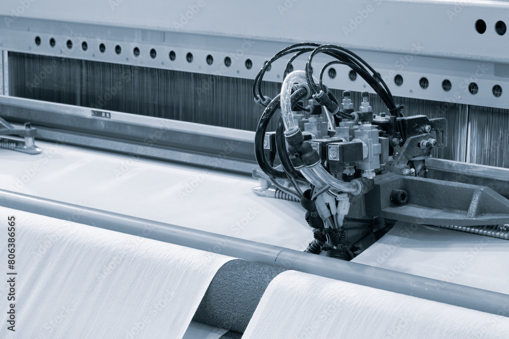 Leinwandbilder a machine is weaving a fabric with many different colored threads. the machine is blue and white