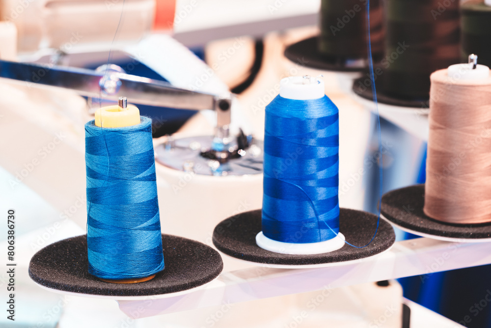 Aufkleber three spools of thread are displayed on a table. the blue spool is the tallest and the other two are