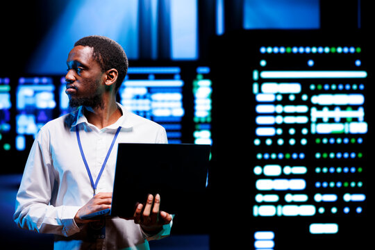 IT developer in server room using laptop to find firewall misconfigurations affecting mainframes performance and connectivity, leading to sluggish data transfer rates and poor client communication - Powered by Adobe