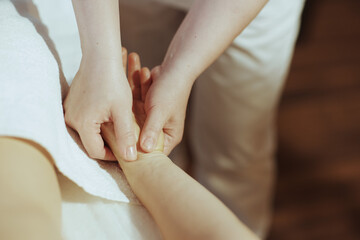 Massage therapist in massage cabinet massaging clients hand