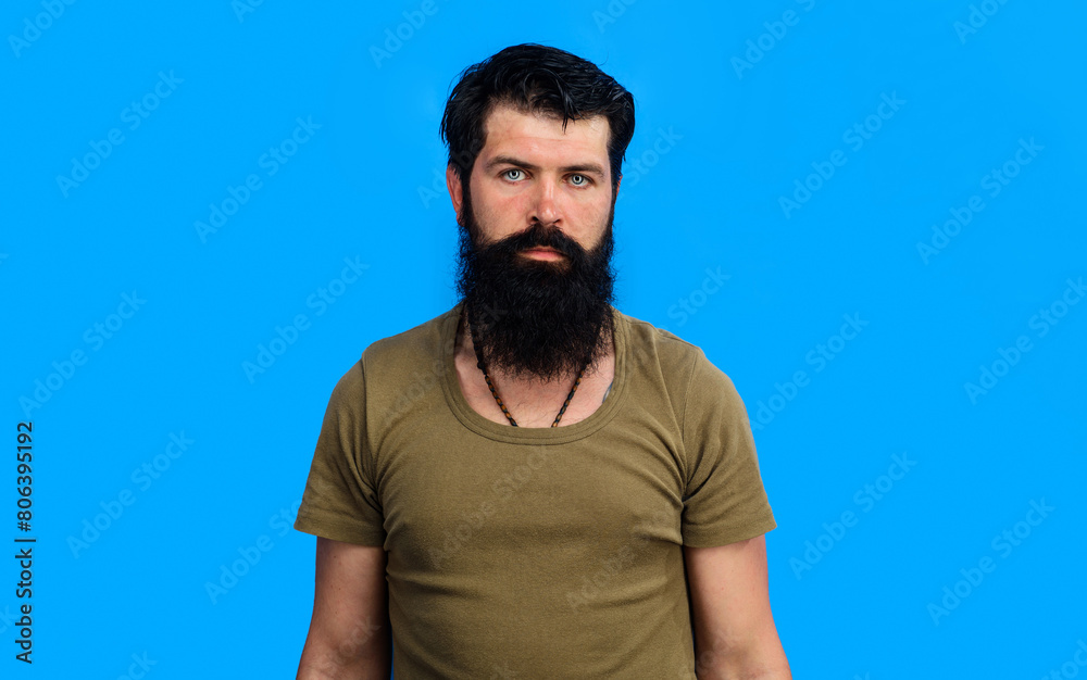 Wall mural Man portrait. Serious bearded man in t-shirt. Handsome confident man with beard and mustache in casual clothes. Brutal bearded man with stylish hairstyle. Sporty healthy guy with black hair and beard.