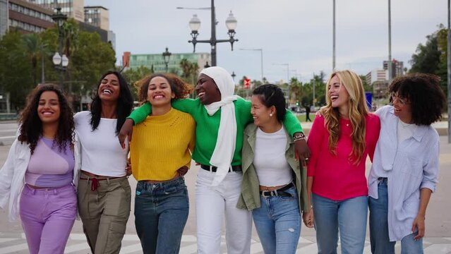Group of young diverse friends walking relaxed and talking to each other and sharing a fun leisure time enjoying friendship together in city. Generation z youth community and people union