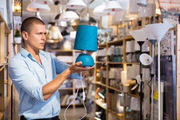 Man is choosing new table lamp for her home in the store