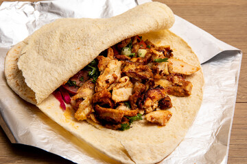 An open pita stuffed with middle Eastern chicken shawarma