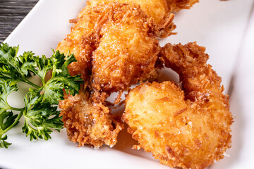 Close up of a plate of deep fried coconut shrimp with a red dipping sauce