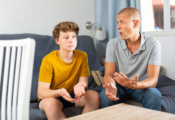 Father and his son sitting on sofa in living room and talking