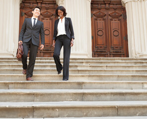 Business or legal professionals walking down courthouse steps outdoors.