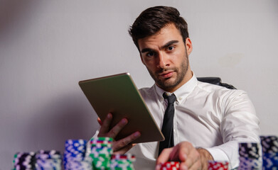 Closeup shot of a handsome man in white shirt and tie playing poker online after long day at work 