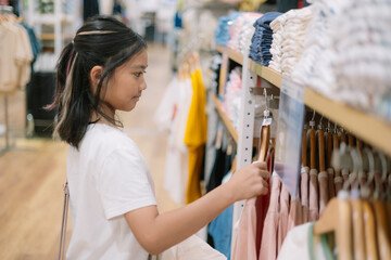 A young girl is shopping for clothes in a store