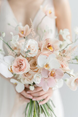 Wedding bouquet of white orchids, peonies and chrysanthemums in the hands of the bride