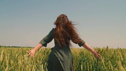 Farmer woman happily runs through wheat field with ears of wheat. Beautiful carefree woman enjoys...