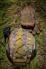 Helmet, walkie talkie and tactical gloves on the ground on a sunny day, top view. Military equipment, military protection