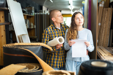 Young positive woman and man discussing shopping list in building materials store