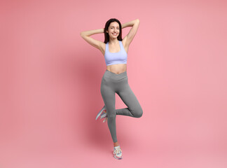 Happy young woman with slim body posing on pink background