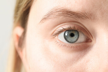 Macro photo of woman with beautiful eyes on light background