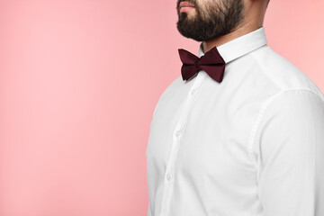 Man in shirt and bow tie on pink background, closeup. Space for text