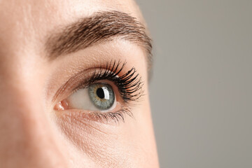 Macro photo of woman with beautiful eyes on grey background. Space for text