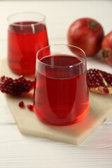 Tasty pomegranate juice in glasses and fresh fruits on white wooden table, closeup