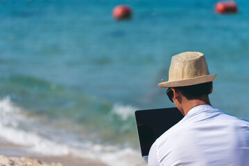 Man traveler use laptop on summer beach blue sky. Asian man wear casual short pants tropical shirt...