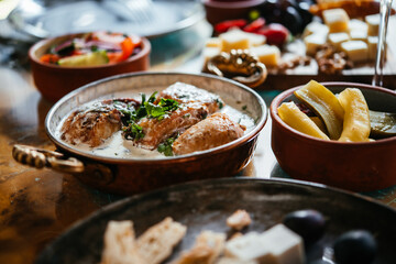 Dinner table served with georgian dish shkmeruli - chicken with creamy garlic sauce with wine and...