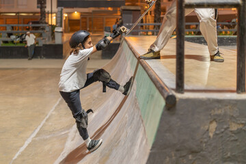 Coach helping his student in skateboarding lessons at the skate park