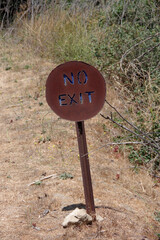 Rusty metal sign NO EXIT at a rural dirt road