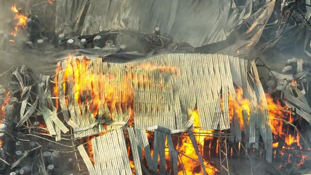 Chaos reigns in the industrial inferno, flames devouring metal and debris. Thick smoke cloaks the wreckage, a testament to the relentless fury unleashed upon the scene.
