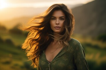 Naklejka premium A Serene Portrait of a Young Woman with Flowing Hair Standing Majestically in Front of a Lush Green Valley at Sunset