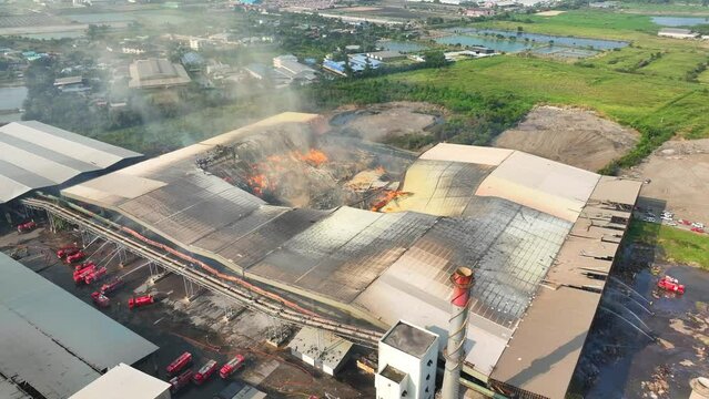 Amidst the chaos of raging flames, fire trucks converge, relentlessly battling the inferno. Their streams of water clash with the fiery menace, a symphony of effort to quell the industrial blaze.
