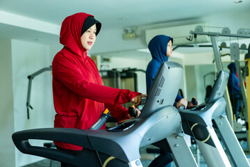 Muslim sport, Happy cheerful Asian Muslim mother and daughter Running on Treadmill. Energetic Fit...